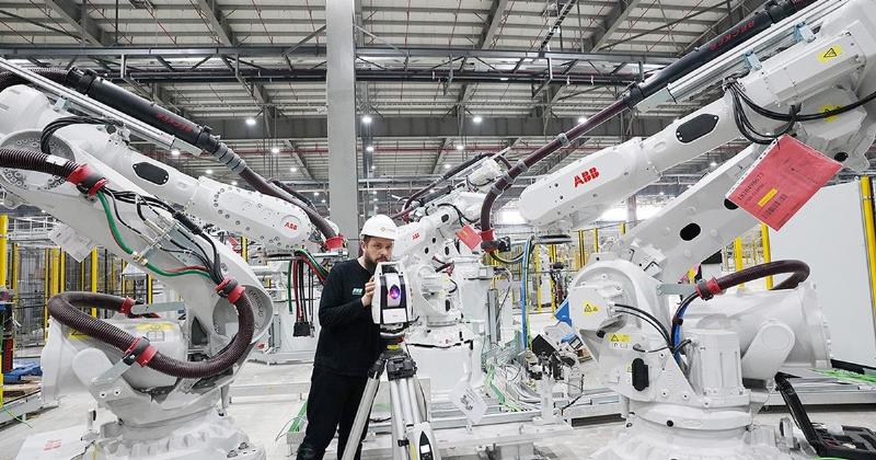 Cánh tay robot đang thực hiện hàn điểm trên thân xe ô tô tại xưởng thân vỏ